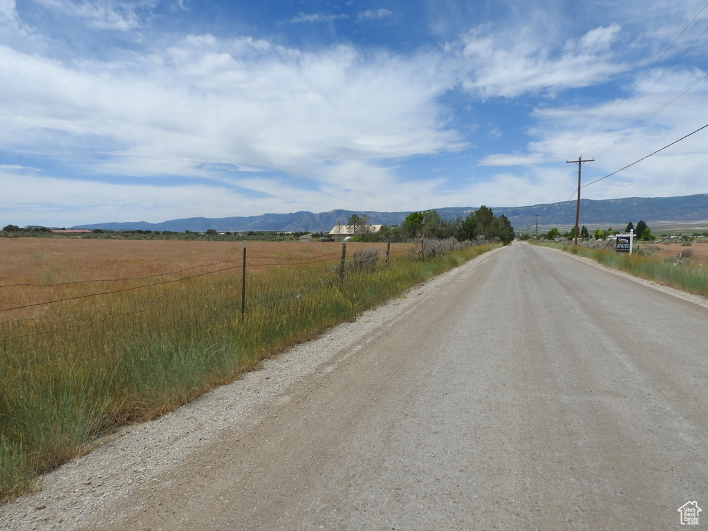 View of dirt / gravel road with a mountain view and a view of rural / pastoral area
