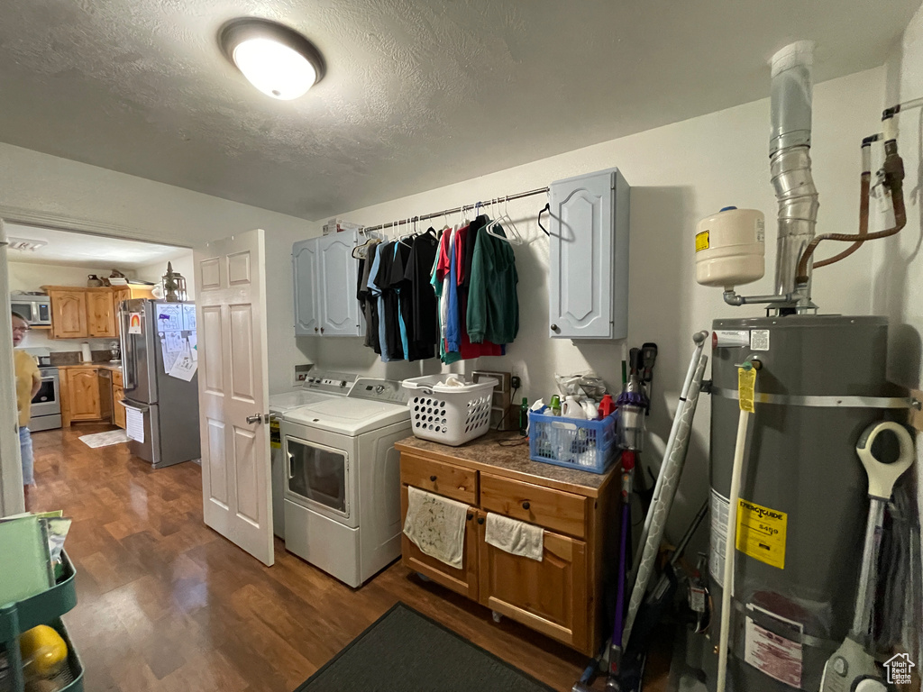 Washroom featuring strapped water heater, independent washer and dryer, dark wood-style flooring, a textured ceiling, and cabinet space