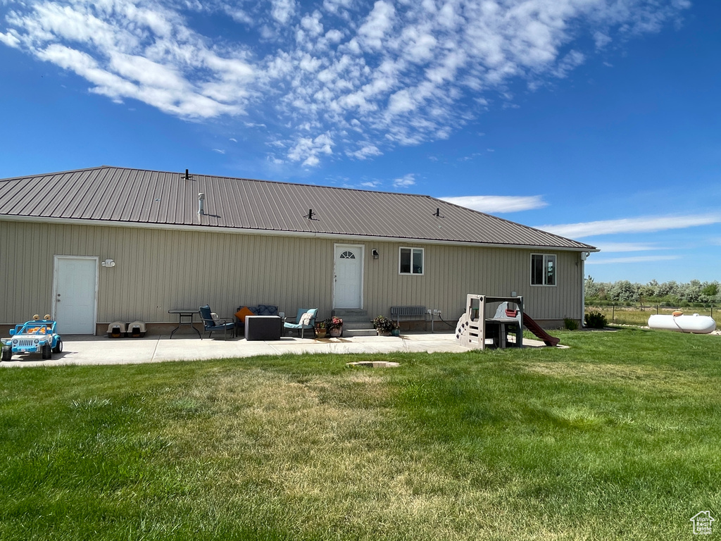 Rear view of house with entry steps, a patio area, a yard, and a metal roof