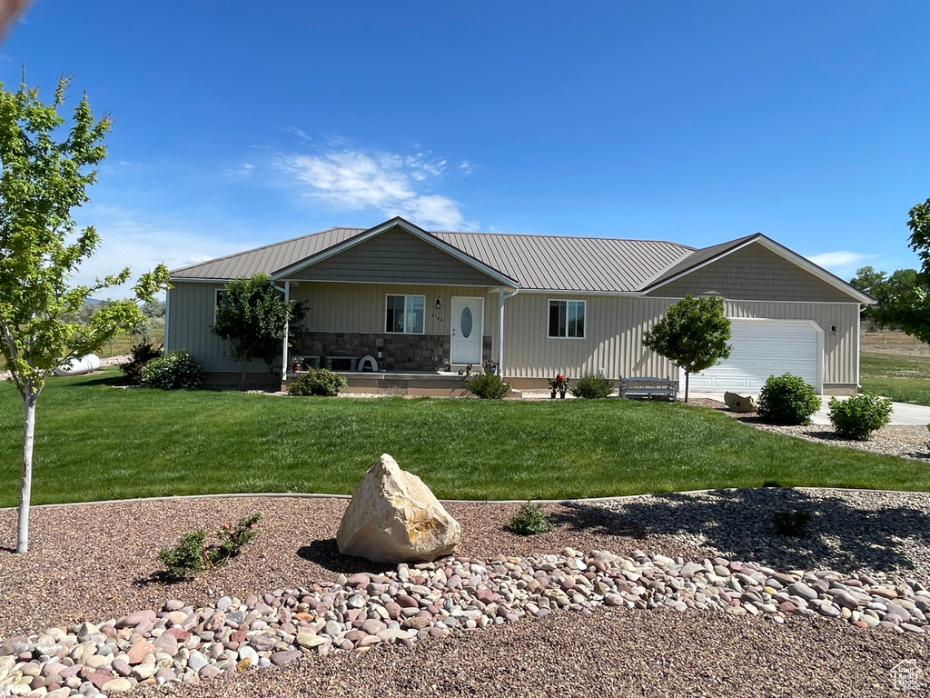 Ranch-style house with a front lawn, an attached garage, and a metal roof