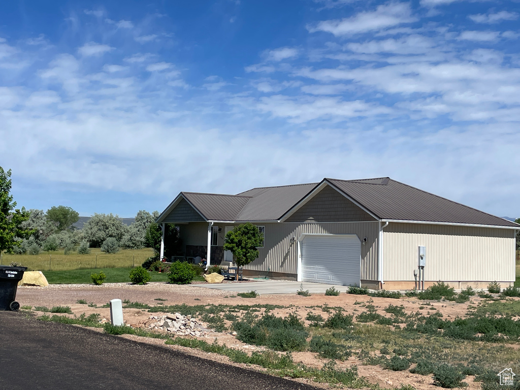 View of front of house with driveway, an attached garage, and a metal roof