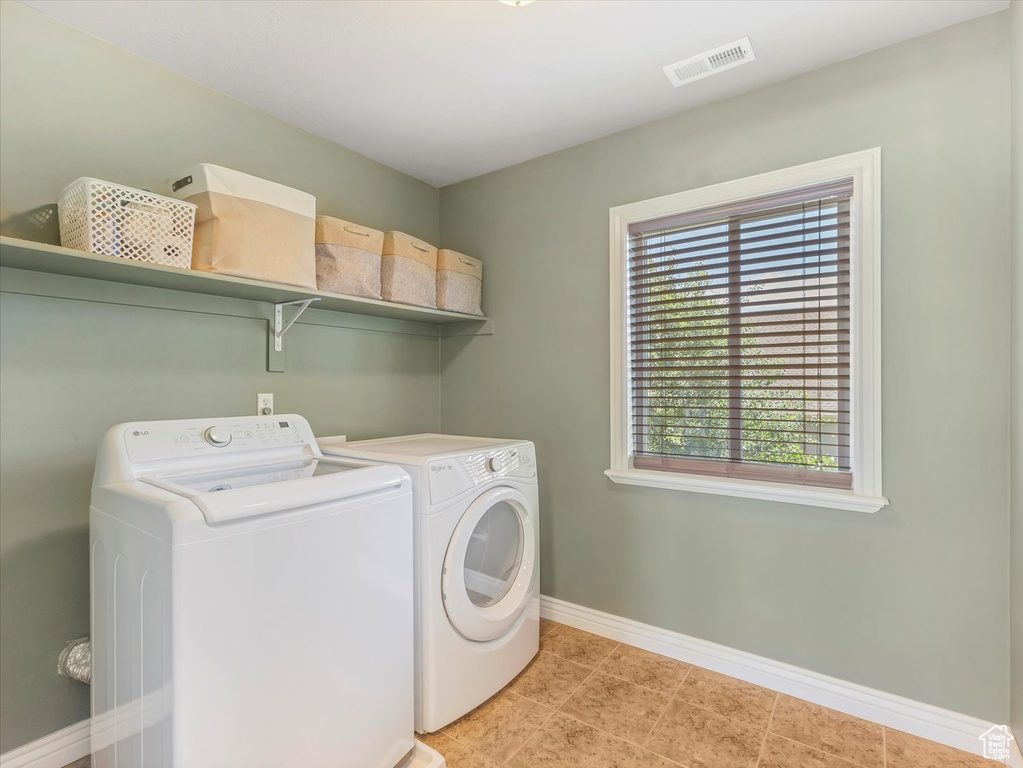 Washroom with separate washer and dryer and light tile patterned flooring