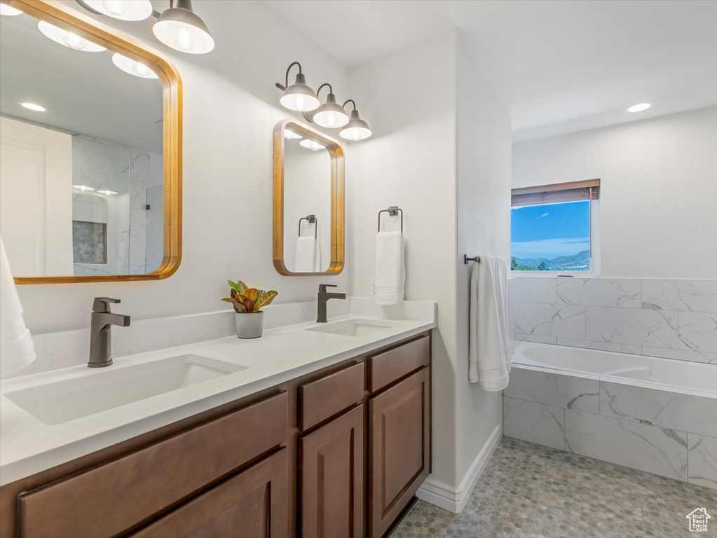 Bathroom featuring a bath, double vanity, and recessed lighting