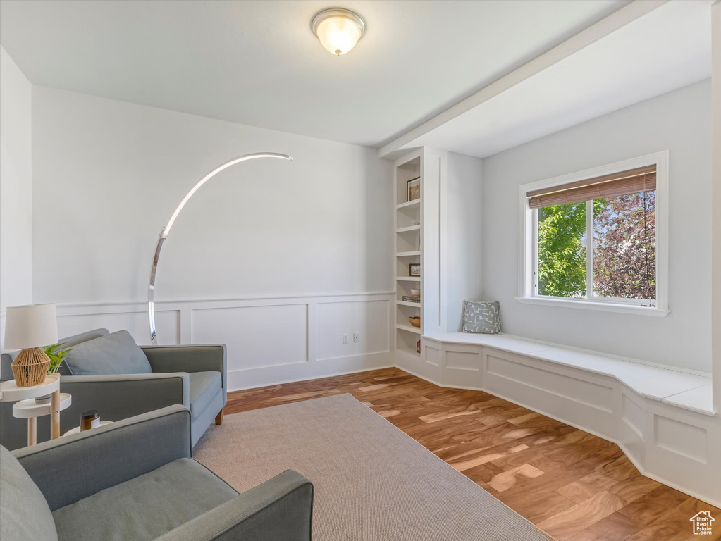 Sitting room featuring light wood-style flooring, wainscoting, and a decorative wall