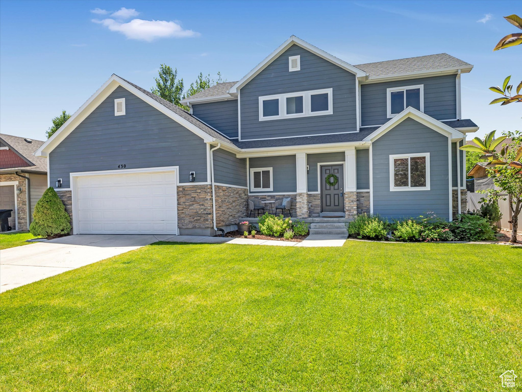 Craftsman inspired home featuring a garage, concrete driveway, a front lawn, and a shingled roof