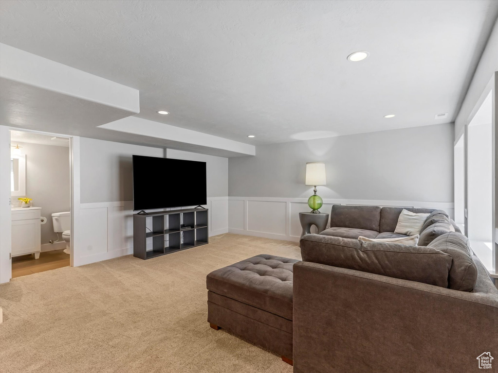 Living area with light colored carpet, recessed lighting, wainscoting, and a decorative wall