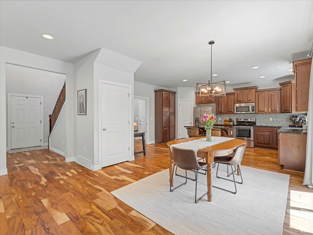 Dining room with a chandelier, stairs, light wood-style flooring, and recessed lighting