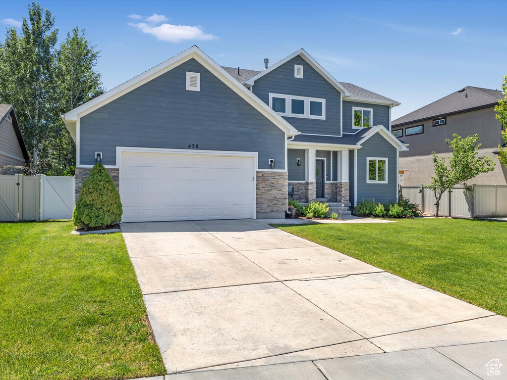 Craftsman inspired home featuring stone siding, an attached garage, a gate, concrete driveway, and covered porch