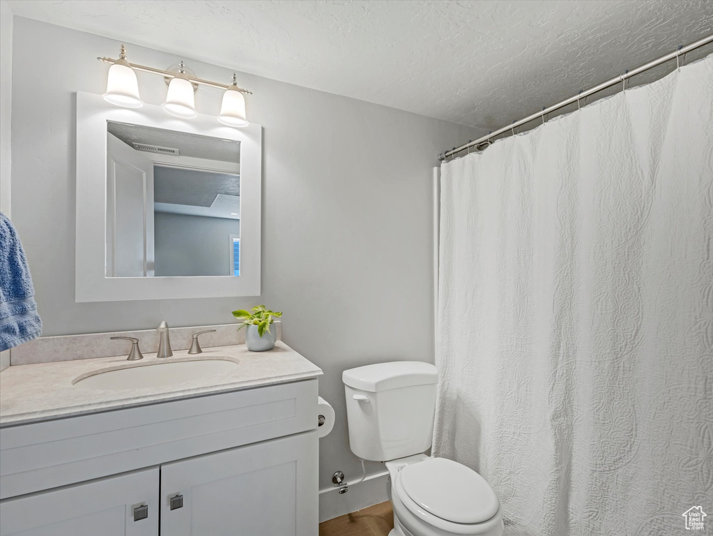 Bathroom with vanity, a textured ceiling, and curtained shower
