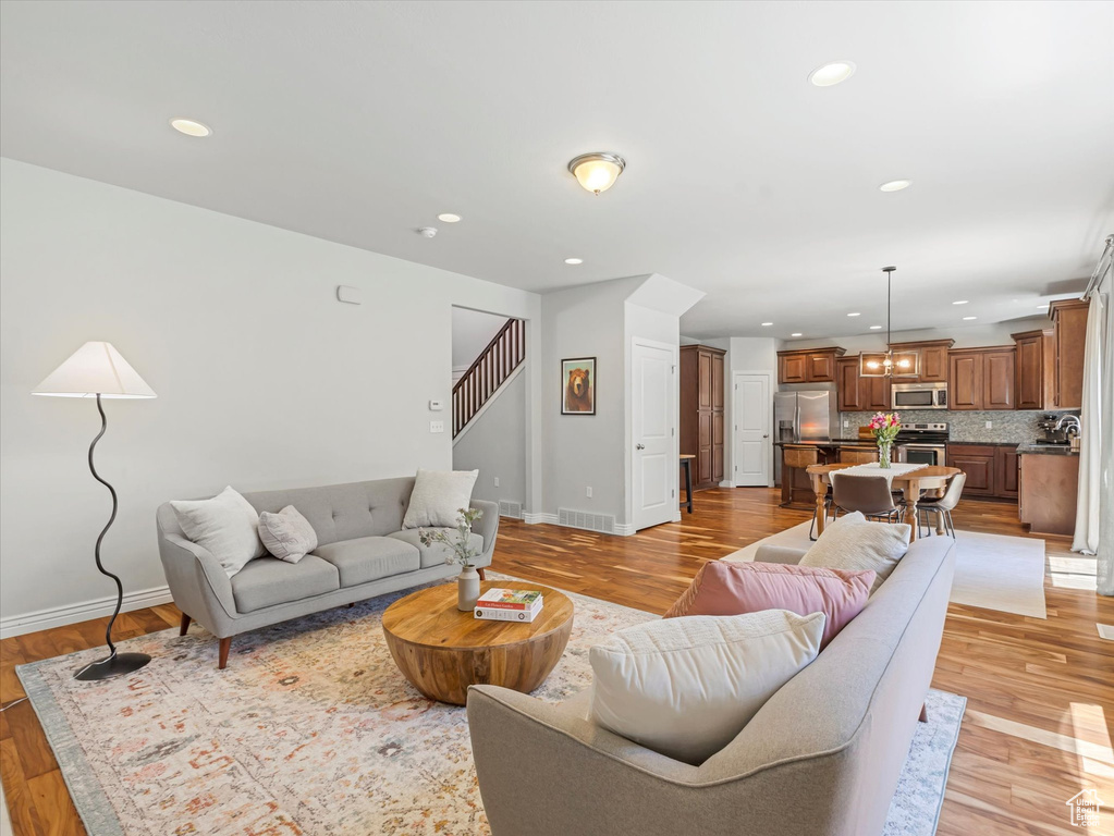 Living area with light wood-style flooring, stairway, and recessed lighting