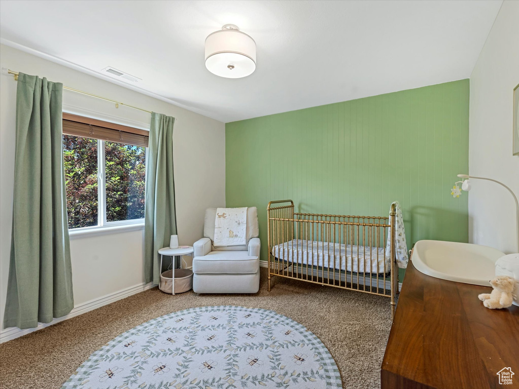 Carpeted bedroom with a crib and baseboards