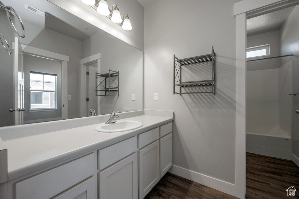 Bathroom featuring wood finished floors, vanity, and shower / washtub combination