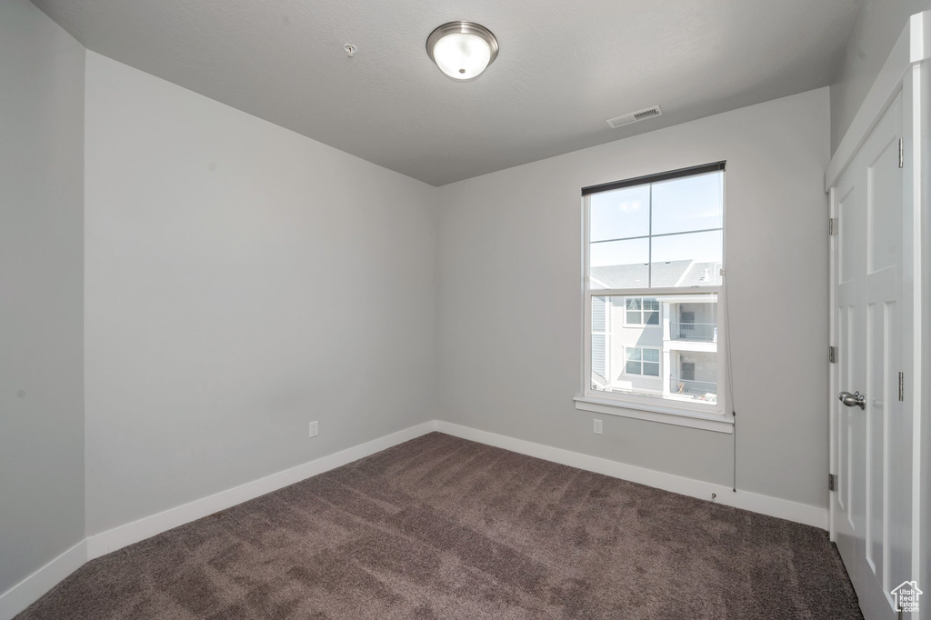 Spare room with dark carpet and baseboards