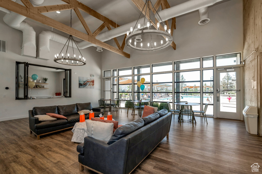 Living room featuring a high ceiling, a chandelier, healthy amount of natural light, beamed ceiling, and wood finished floors