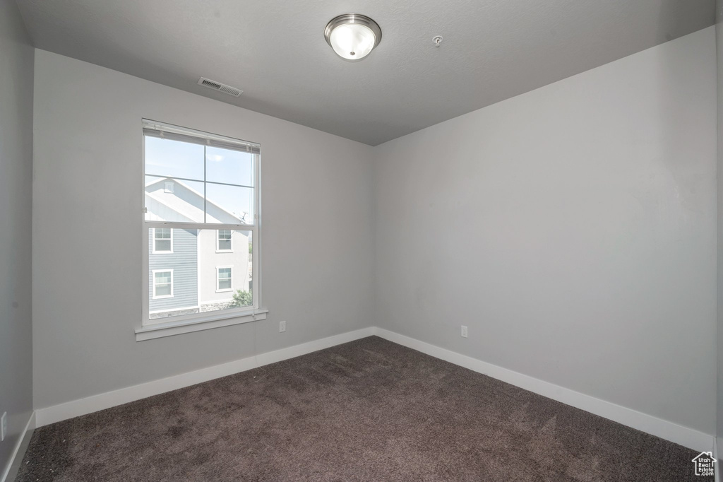 Spare room with dark carpet and baseboards