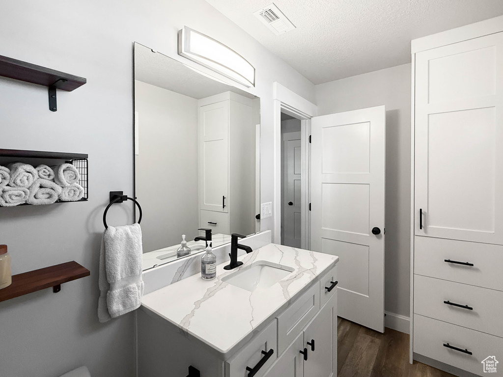 Bathroom with wood finished floors, vanity, and a textured ceiling