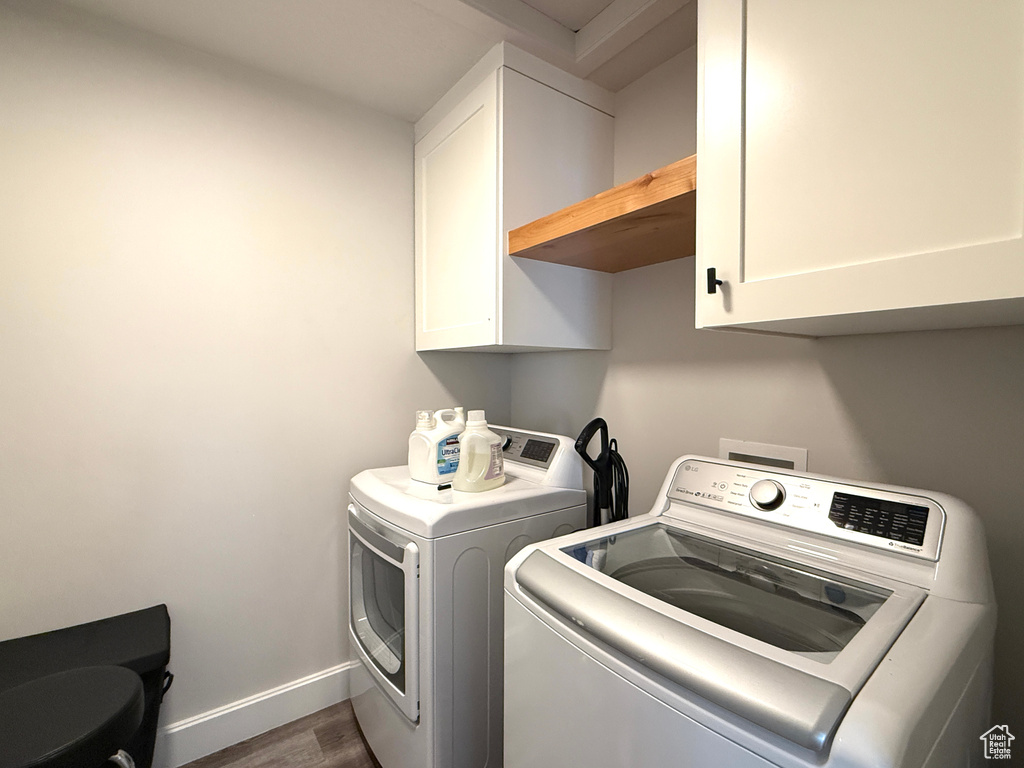 Laundry area featuring cabinet space, washer and clothes dryer, and wood finished floors