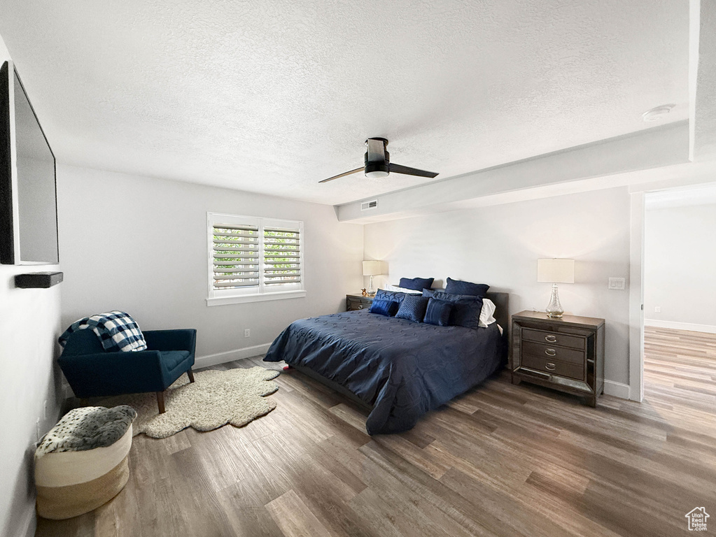 Bedroom with wood finished floors, a textured ceiling, and a ceiling fan