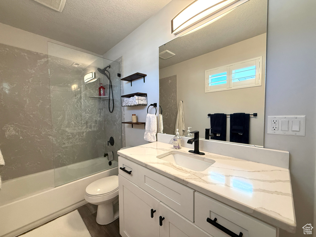 Full bath featuring vanity, bathtub / shower combination, wood finished floors, and a textured ceiling