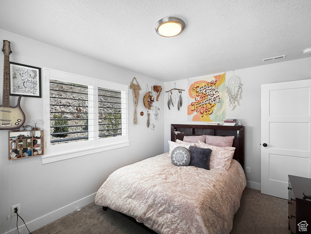 Carpeted bedroom with a textured ceiling and baseboards
