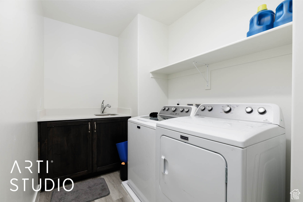 Laundry room featuring cabinet space, washer and clothes dryer, and light wood-type flooring