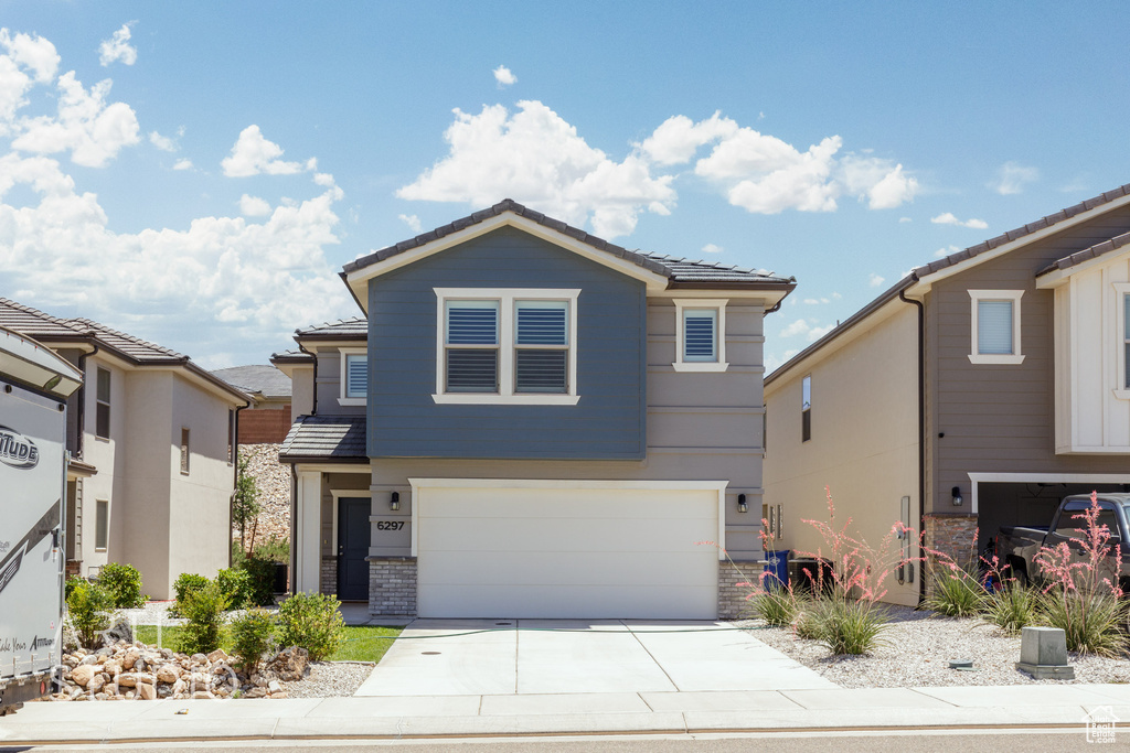 View of front of property with concrete driveway, an attached garage, and a tiled roof