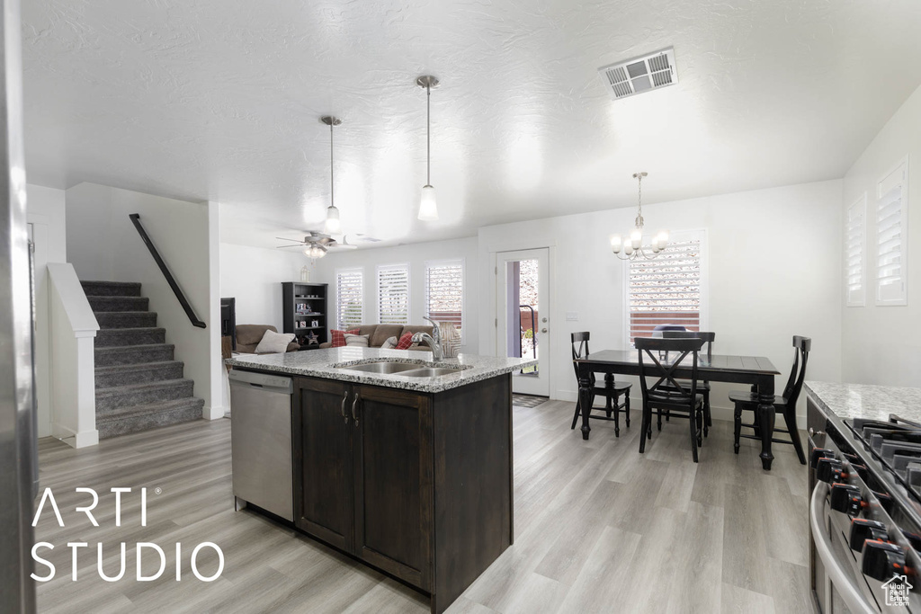 Kitchen with stainless steel appliances, light wood-type flooring, dark brown cabinets, a center island with sink, and open floor plan