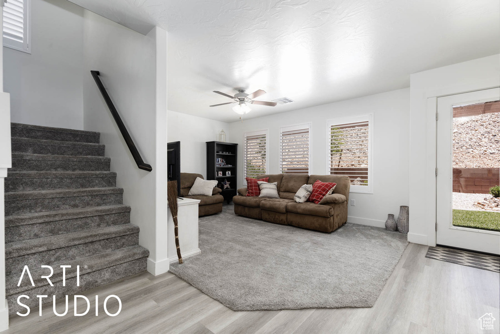 Living room with wood finished floors, stairs, and a ceiling fan