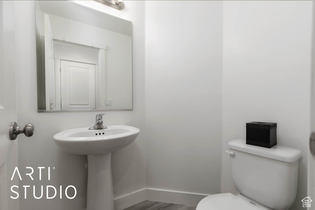 Half bathroom featuring toilet and wood finished floors