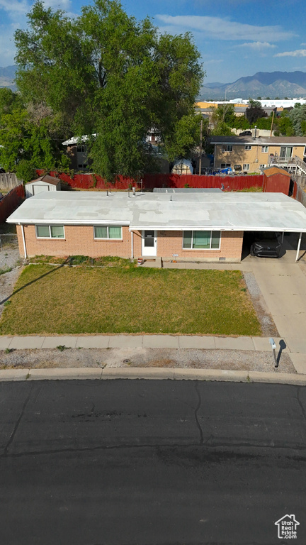 View of front facade featuring a mountain view, a front yard, and driveway