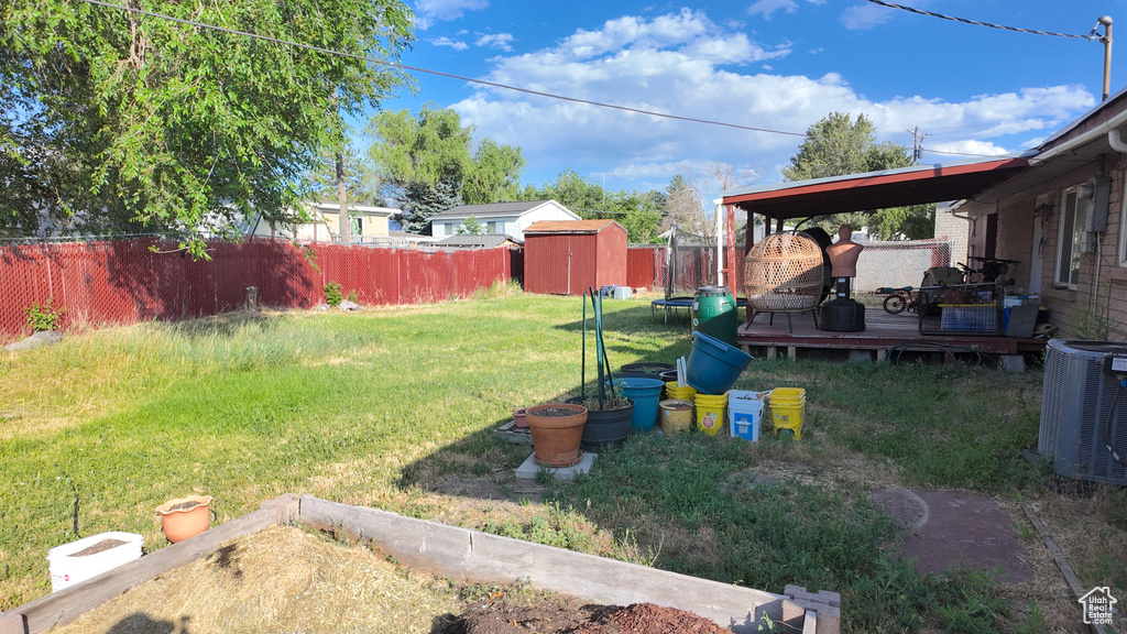 Fenced backyard featuring a storage shed and a deck