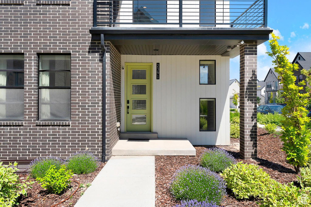 Entrance to property with brick siding and a balcony