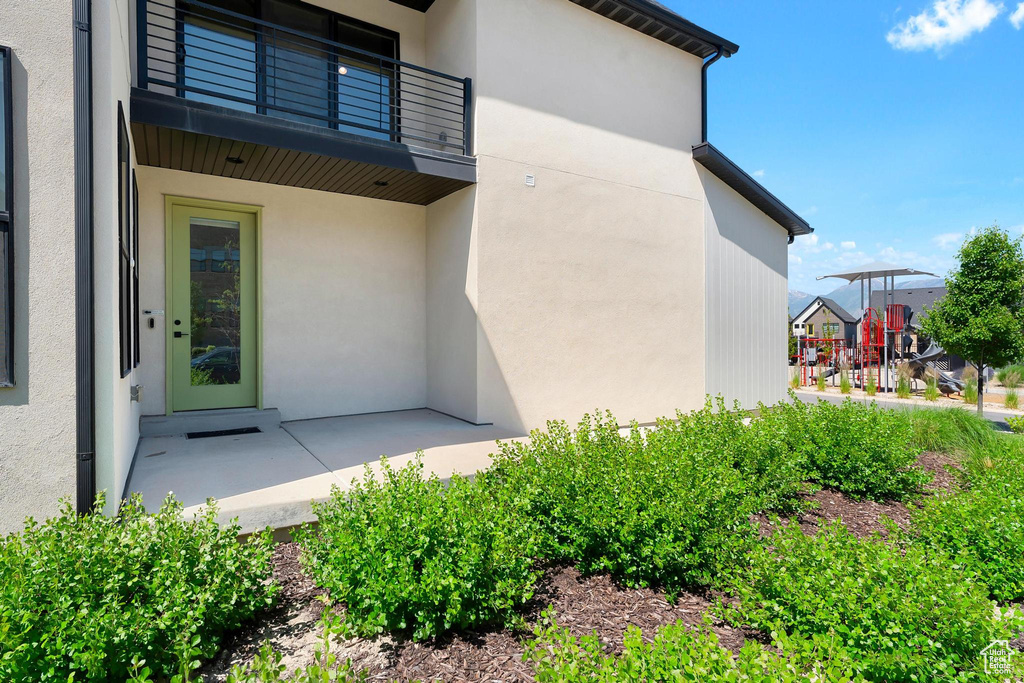 View of exterior entry featuring a balcony and stucco siding