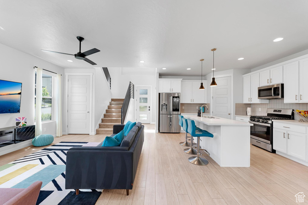 Living room featuring a ceiling fan, light wood-style flooring, stairway, and recessed lighting