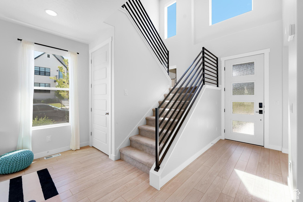 Foyer entrance with stairs, light wood-type flooring, a towering ceiling, and recessed lighting