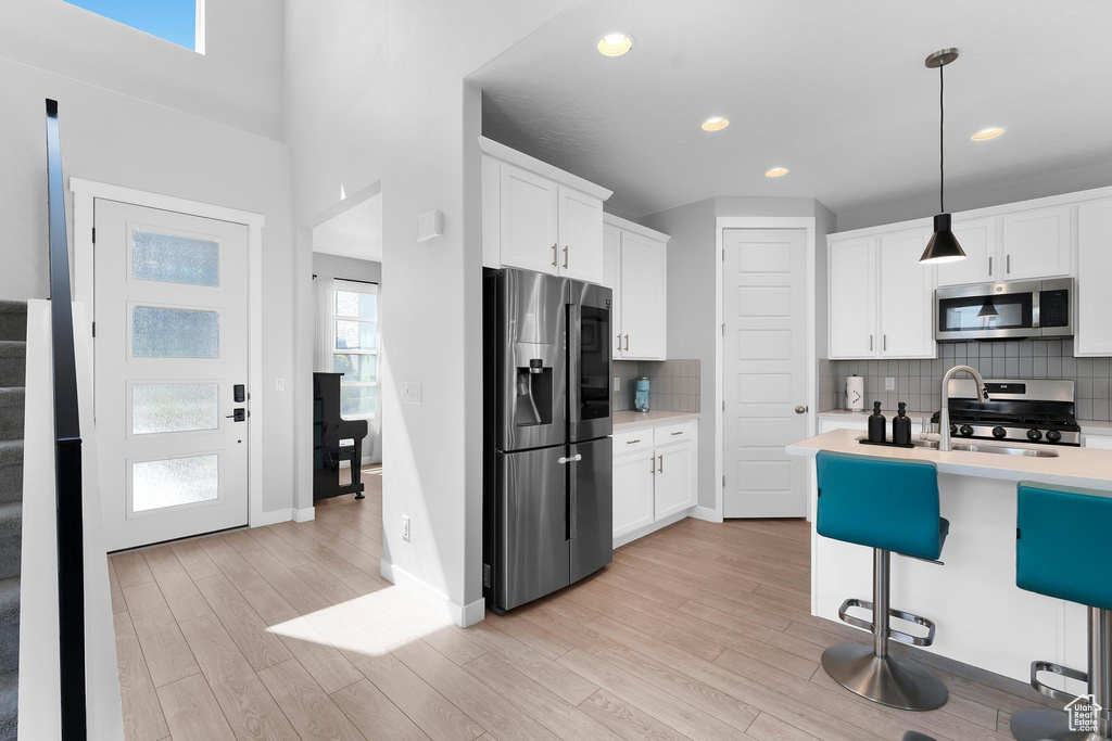 Kitchen featuring appliances with stainless steel finishes, light countertops, light wood-type flooring, white cabinets, and recessed lighting
