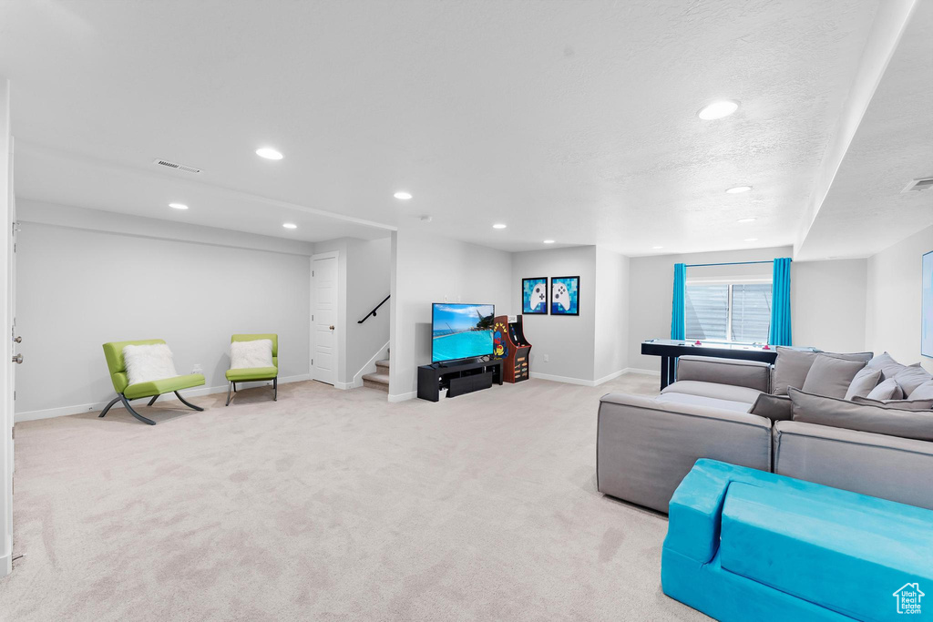 Living area with light carpet, stairs, recessed lighting, and a textured ceiling