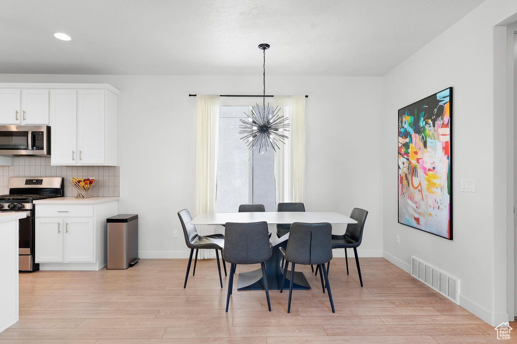 Dining space with light wood-style floors, recessed lighting, and a chandelier