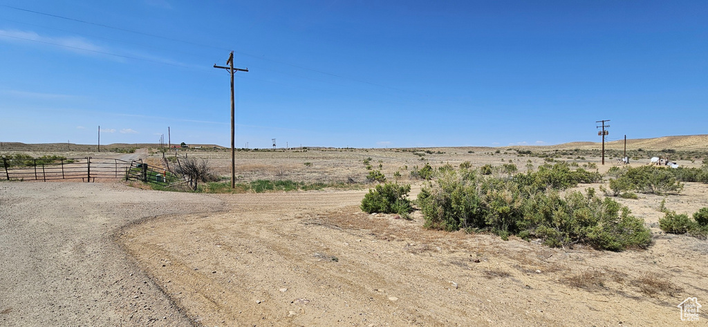 View of dirt / gravel road with a rural view and a gated entry