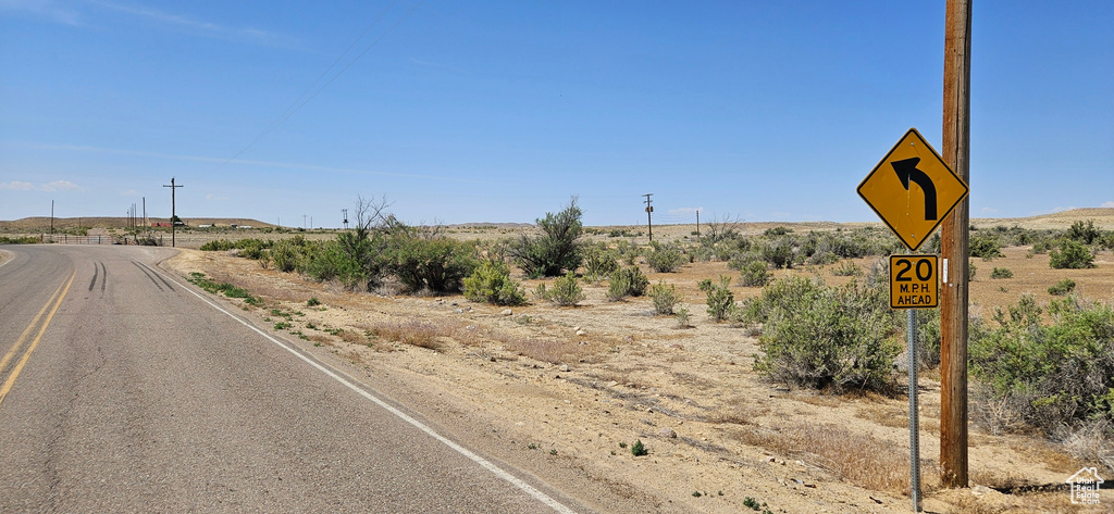 View of asphalt road with a view of rural / pastoral area and traffic signs