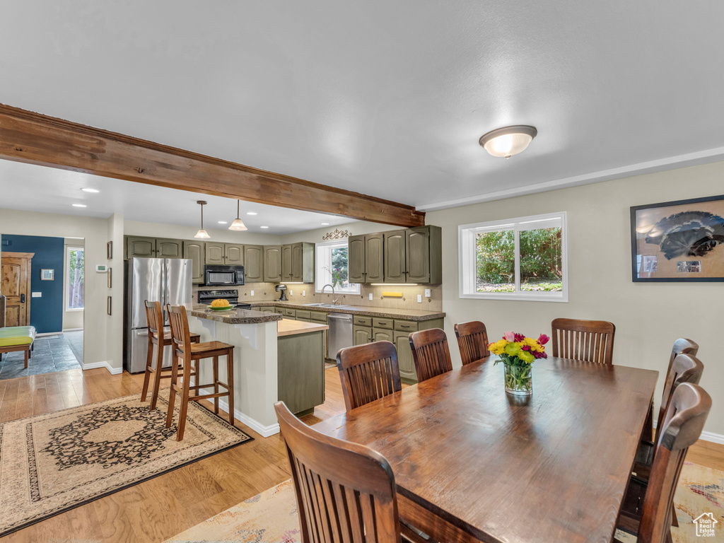 Dining room featuring light wood-style floors, plenty of natural light, recessed lighting, and beamed ceiling