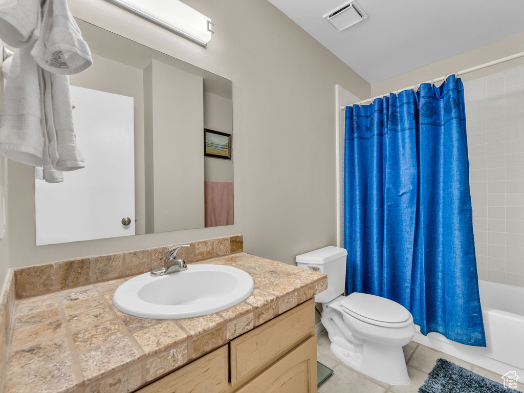 Bathroom with vanity, shower / tub combo with curtain, and tile patterned floors