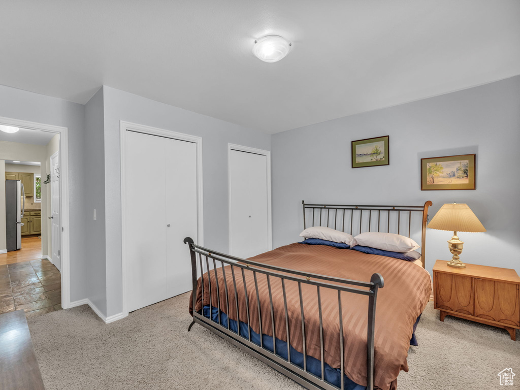 Bedroom featuring freestanding refrigerator, two closets, and carpet floors