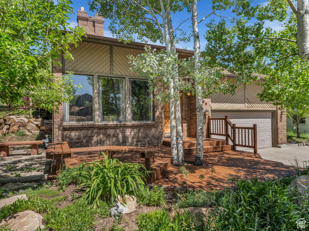 Mid-century home featuring driveway, a chimney, and brick siding