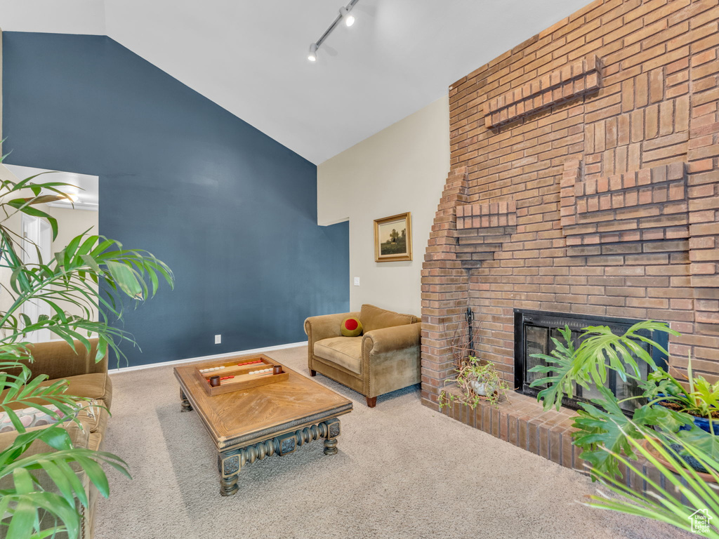 Living room with high vaulted ceiling, carpet flooring, rail lighting, and a fireplace
