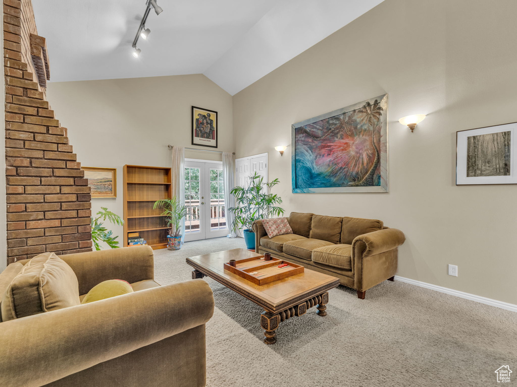 Living room featuring track lighting, high vaulted ceiling, carpet floors, and french doors