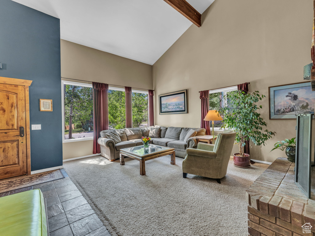 Living area featuring high vaulted ceiling, stone tile flooring, and beamed ceiling