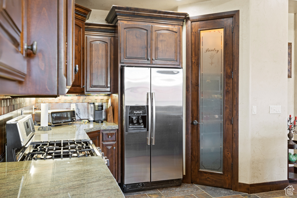 Kitchen featuring stainless steel appliances, backsplash, and dark stone finish flooring