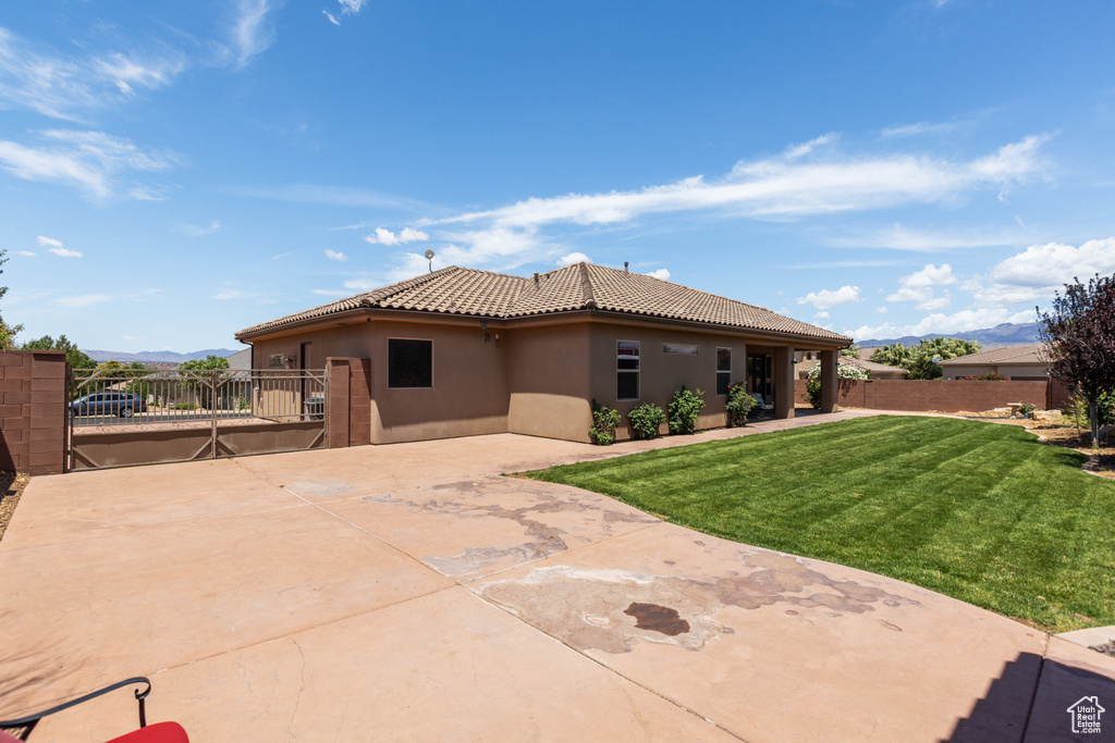 Rear view of property with stucco siding, a mountain view, a patio, a tile roof, and a gate