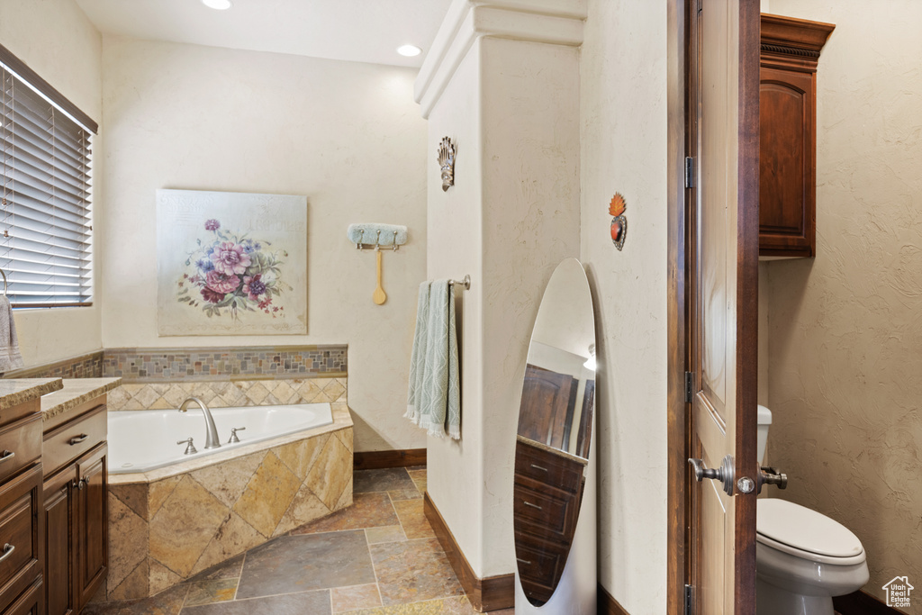 Full bathroom featuring stone tile flooring, a bath, vanity, and recessed lighting